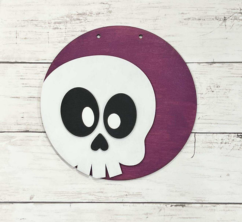 Circular sign with a skull design on a purple background, placed on a wooden surface.