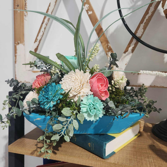 Colorful flower arrangement in a blue container on books with a rustic background
