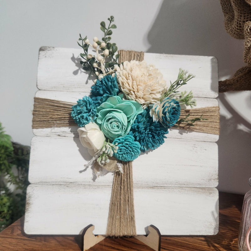 Decorative wooden cross with floral arrangement on a stand