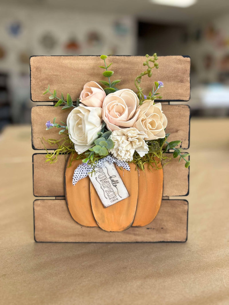 Decorative sola flowers and pumpkins on a wooden block background