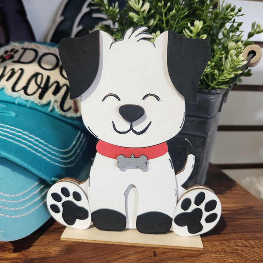 Wooden dog figurine with a red collar on a wooden stand, with a 'Dog Mom' hat in the background.