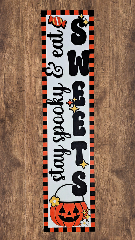 Halloween-themed decorative sign with text and pumpkin design on a wooden background