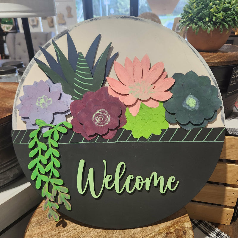 Decorative sign with flowers and 'Welcome' text on a round board.