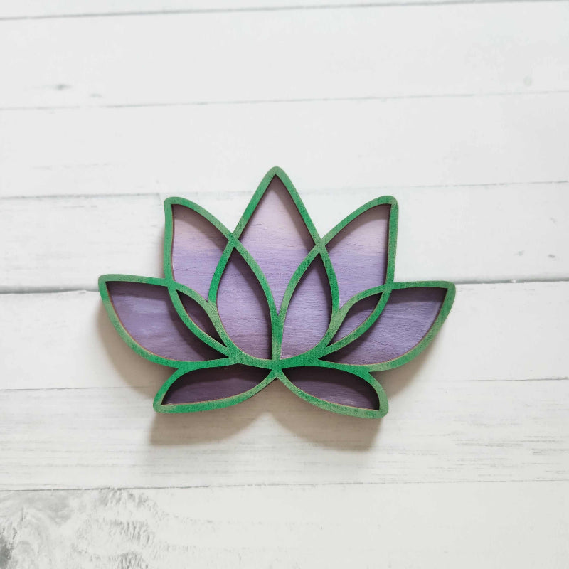 Decorative wall art with a purple and green leaf design on a white wooden background
