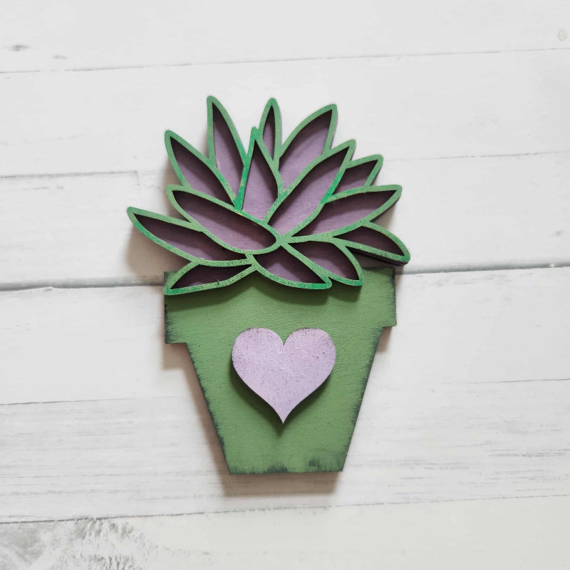 Wooden succulent plant decoration with a heart on a white wooden surface