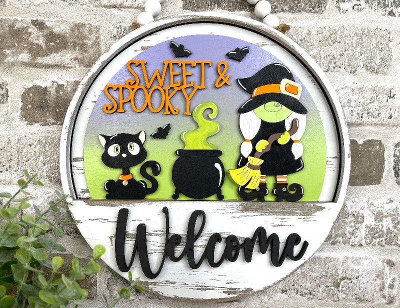 Alt text: Sweet &amp; Spooky interchangeable wooden Halloween Welcome sign insert with a witch, blad bats.ck cat, bubbling cauldron and bats