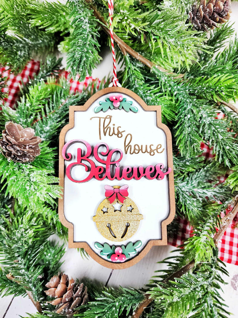 Decorative Christmas ornament with 'This house believes' text on a green Christmas tree.