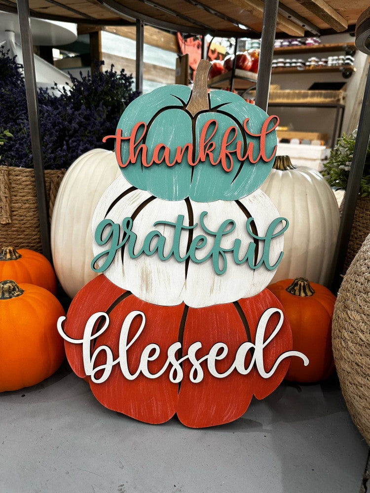 wooden door hanger features three pumpkins stacked with the words thankful grateful blessed
