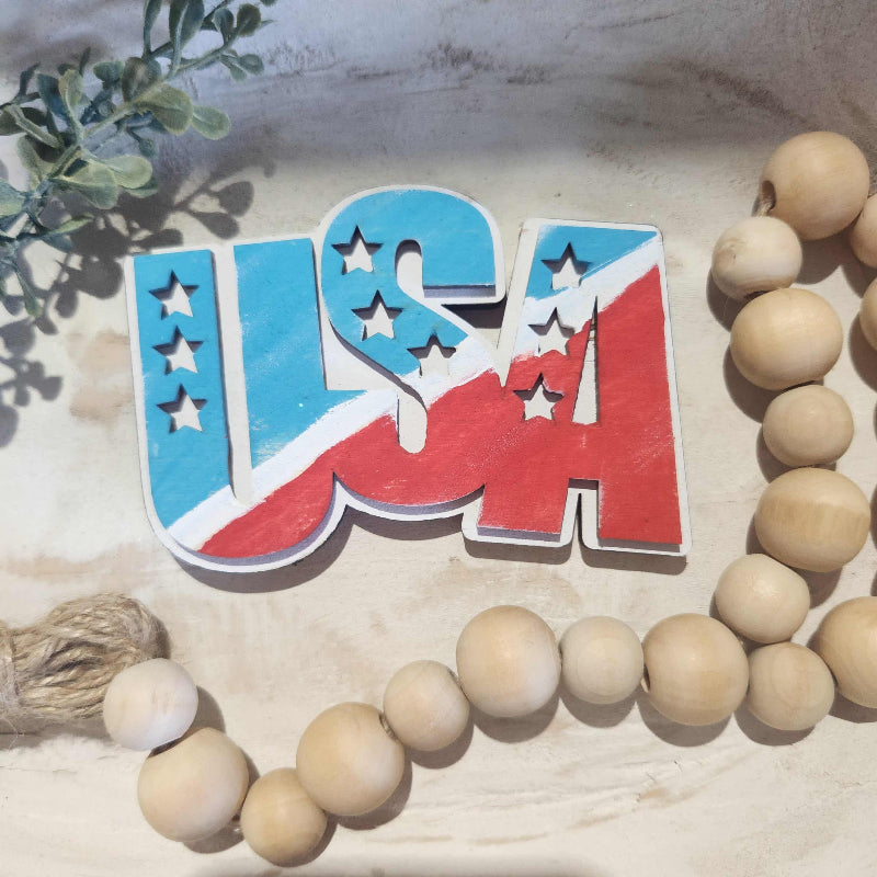 Decorative USA with stars, surrounded by wooden beads on a textured surface.