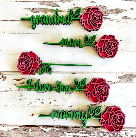 Handcrafted wooden roses in red and green, with personalized text on the stems, displayed against a rustic wooden background.