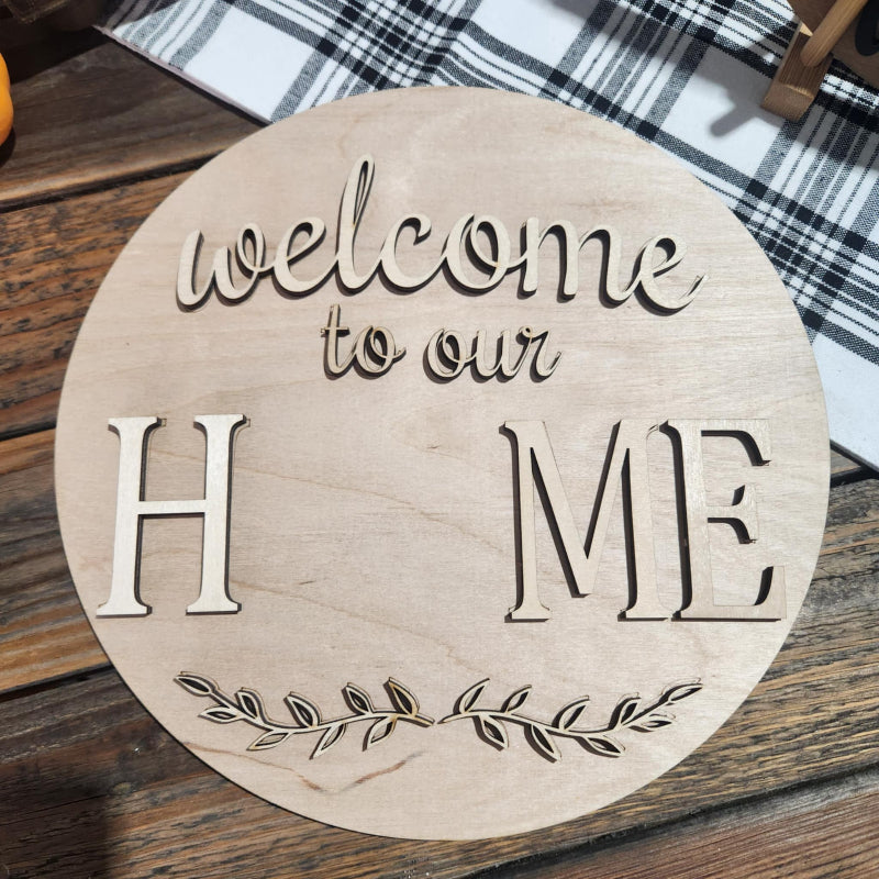 Wooden round sign with 'Welcome to our Home' engraving on a wooden surface.