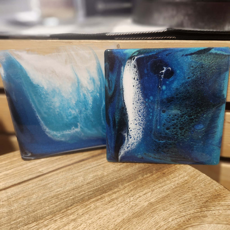 Two blue and white marbled soap bars on a wooden surface