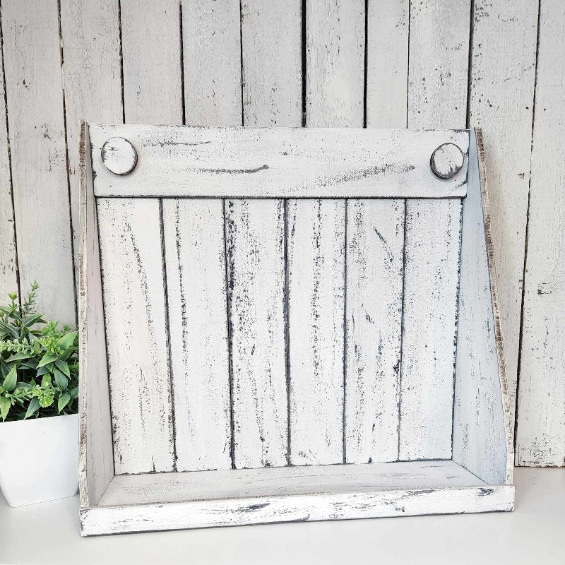 A rustic white wooden shaker box display against a wooden background with a plant to the side.