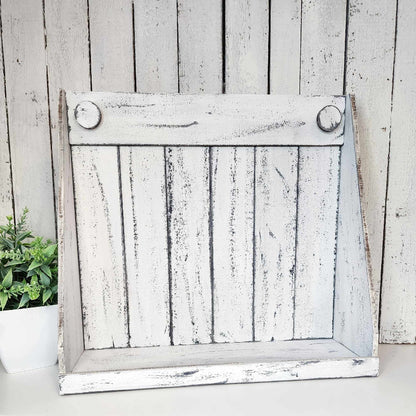 A rustic white wooden shaker box display against a wooden background with a plant to the side.