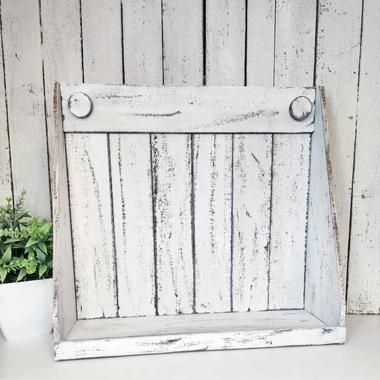 A rustic white wooden shaker box display against a wooden background with a plant to the side.