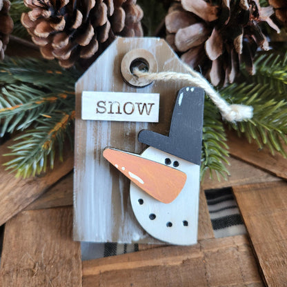 A collection of wooden gift tags with 3D ornaments including a bird, a crown, Santa Claus, a reindeer, a snowman, and a Christmas tree, all with festive messages.