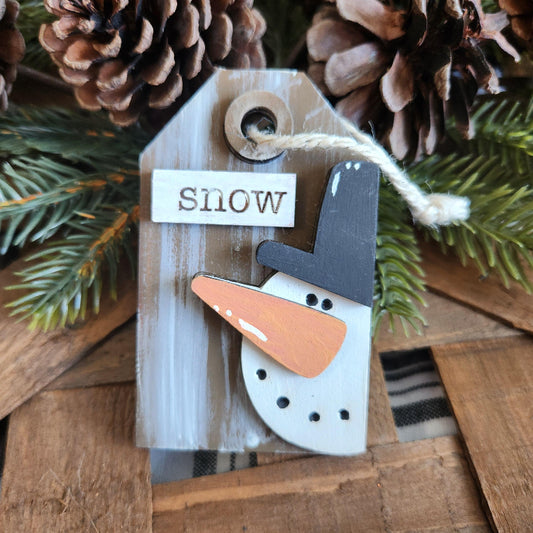 A collection of wooden gift tags with 3D ornaments including a bird, a crown, Santa Claus, a reindeer, a snowman, and a Christmas tree, all with festive messages.
