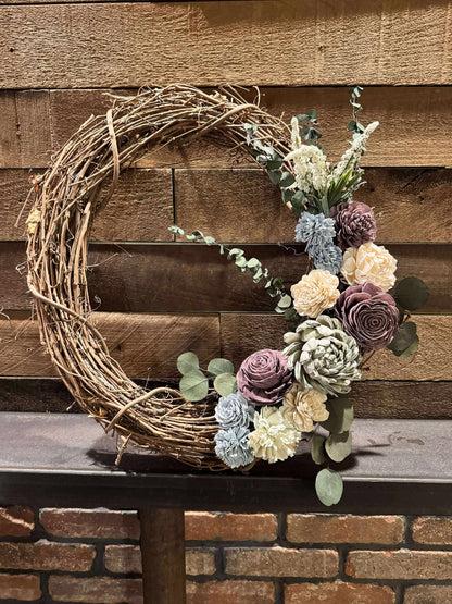 Decorative wreath with flowers and succulents on a wooden surface