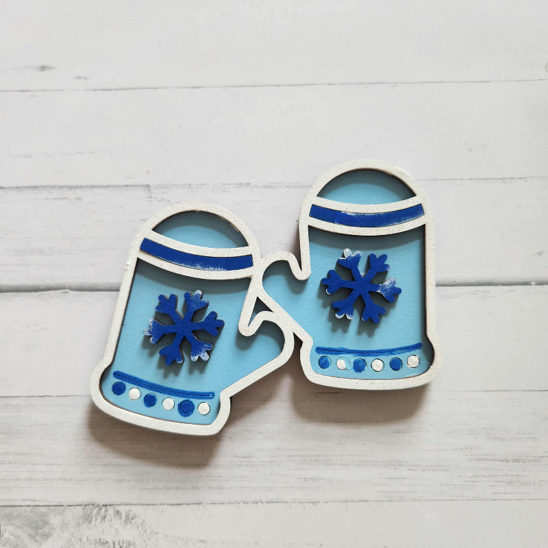 Blue mittens with snowflakes on a light wooden background