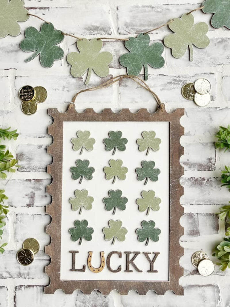 Decorative wall hanging with shamrock pattern and 'Lucky' text on a white wooden background.