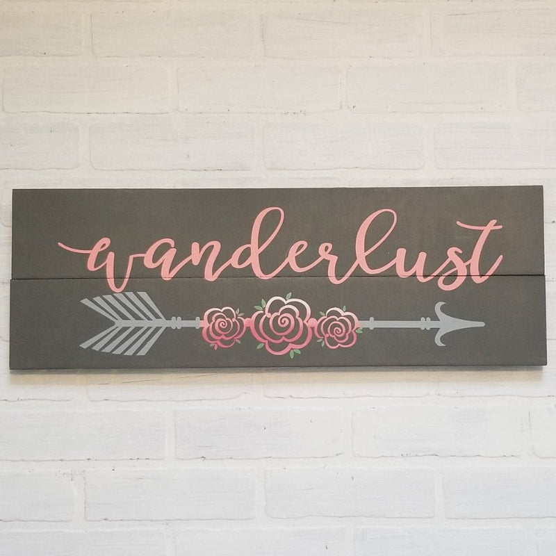 A decorative plank design featuring the word 'WANDERLUST' in pink letters on a gray background, with a pink floral design and a green arrow symbol on the side.